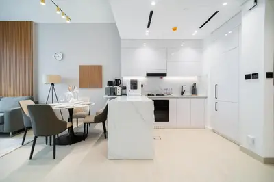 a white kitchen and dining room with a table and chairs at SettlerHomes - Chic JVC Cityview Near Heart of Dubai in Dubai