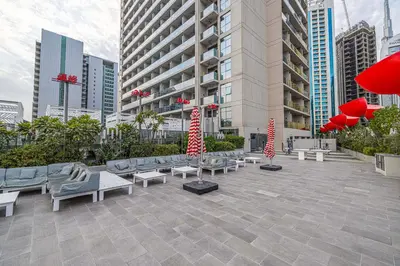 a courtyard with benches and red umbrellas in a city at Upscale 2BR in Lively Building in Dubai