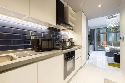 a kitchen with white cabinets and blue tiles on the wall at Cozy Studio Steps from Dubai Mall & Burj Khalifa in Dubai