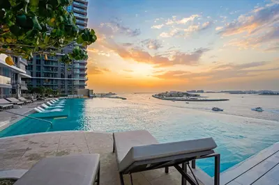 a swimming pool next to a beach with a sunset at Private Beach-Infinity Pool-Lux Beachfront in Dubai