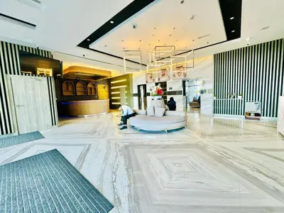 a lobby with a white marble floor and a person sitting on a couch at Bab al qarya in Dubai