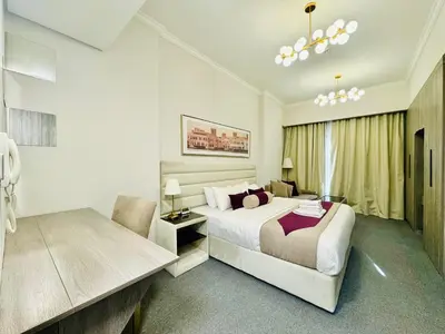 a white bedroom with a bed and a chair at Bab al qarya in Dubai