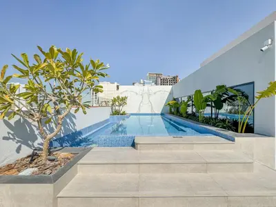 a swimming pool with stairs leading to a building at Luxury 1BR Haven Chic & Cozy Stay in JVC in Dubai