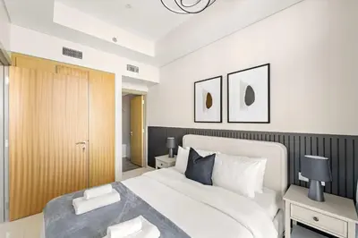a bedroom with a white bed and a wooden cabinet at Silkhaus Luxury 2BDR at Aykon City in Business Bay in Dubai