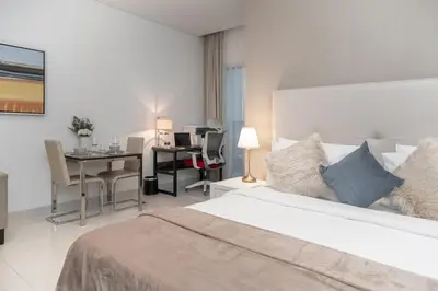 a white bedroom with a bed and a desk and a desk at Cozy and elegant Studio in Business Bay in Dubai
