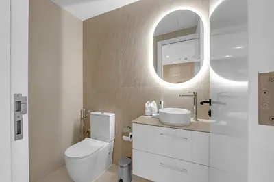 a bathroom with a toilet and a sink and a mirror at Waves - Charming Apt With Balcony Steps From The Beach in Dubai