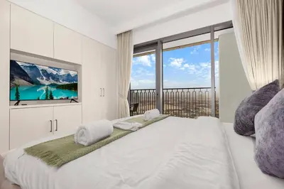 a white bedroom with a large bed and a tv at Elegant 1BR in Heart of Dubai, Walk to Top Malls in Dubai
