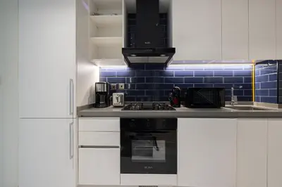 a kitchen with white cabinets and a black stove at Luxury Studio Near Dubai Mall few mints walk in Dubai