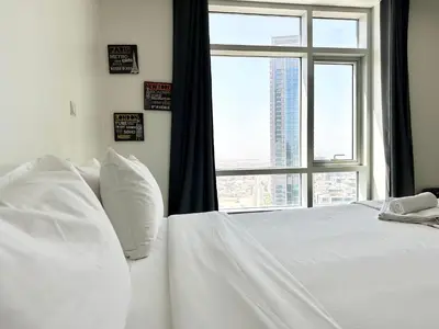 a bedroom with a white bed with a window at The Lofts West Downtown - 2 Minutes Walk to Burj Khalifa-Dubai Mall 1BDR in Dubai