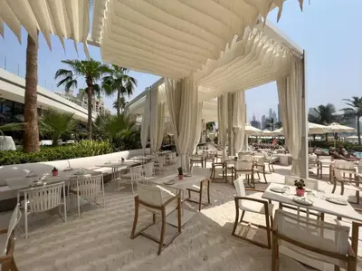 a restaurant with white tables and chairs and umbrellas at Luxury 1BR in Seven Palm with Beach Access in Dubai