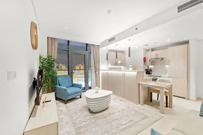 a living room with a blue chair and a kitchen at Luxury 1BR in Seven Palm with Beach Access in Dubai