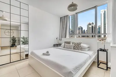 a white bedroom with a large bed and a window at GuestReady - Elegant studio in JLT in Dubai