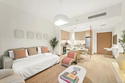 a living room with a bed and a kitchen at Luxe 1BR in Orchid Creek with Balcony Pool & Gym in Dubai