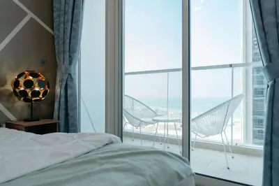 a bedroom with a bed and a balcony with chairs at Beautiful 1 bed apartment Marina I Sleeps 4 in Dubai