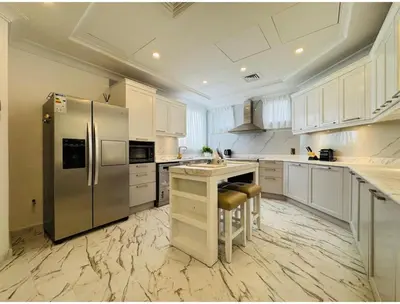 a large kitchen with white cabinets and a stainless steel refrigerator at Palm villas in Dubai