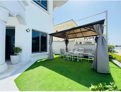 a patio with a table and chairs on a lawn at Palm villas in Dubai