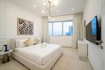 a white bedroom with a white bed and a tv at Lux 5BR Marina Apt with Jacuzzi, Walk to Beach, Gym in Dubai
