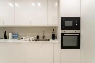 a white kitchen with a sink and a microwave at Lux 5BR Marina Apt with Jacuzzi, Walk to Beach, Gym in Dubai