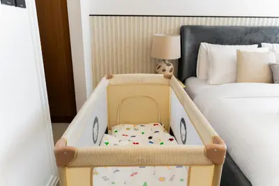 a baby crib sitting next to a bed in a bedroom at SettlerHomes - Serene JVC 1BR With Modern Luxury in Dubai