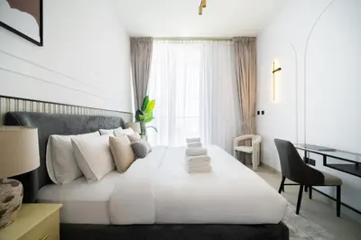 a bedroom with a large white bed and a desk at SettlerHomes - Serene JVC 1BR With Modern Luxury in Dubai