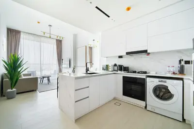 a kitchen with white cabinets and a washer and dryer at SettlerHomes - Serene JVC 1BR With Modern Luxury in Dubai