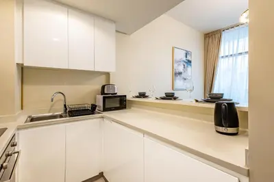 a kitchen with white cabinets and a microwave at Stylish 1BR Business Bay - Near Metro - Balcony with City Views in Dubai