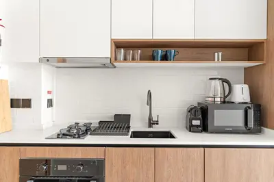 a kitchen with a stove top and a microwave at Chic Dubai Studio with Balcony, Pool, Gym, Free Parking Near Expo Metro in Dubai