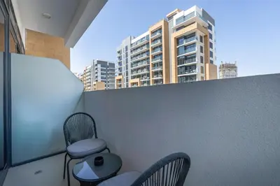 a balcony with two chairs and a table and a building at Dubai Studio - Trendy Interiors - City Views in Dubai