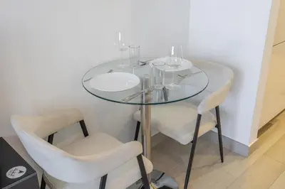 a glass table with two chairs and wine glasses on it at Dubai Studio - Trendy Interiors - City Views in Dubai