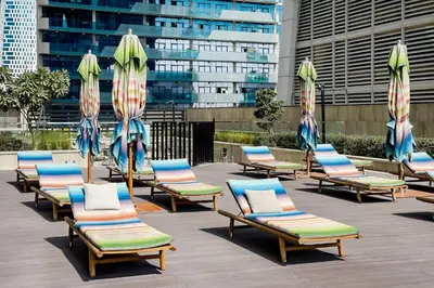 a group of lounge chairs and umbrellas at Convenient 1BR apartment in Business Bay in Dubai