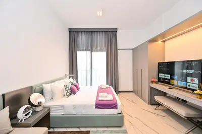 a bedroom with a large bed and a flat screen tv at Charming Studio in Meydan by Deleguest in Dubai
