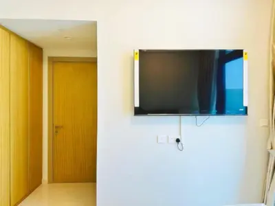 a flat screen tv hanging on a wall with a door at ايكون ستي 2BEd in Dubai