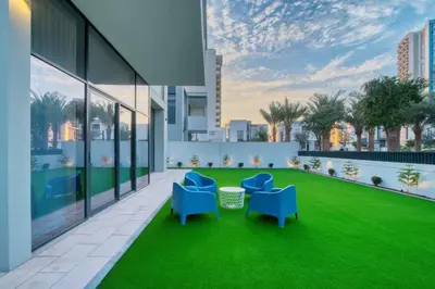 an apartment patio with two blue chairs and grass at Dubai Luxury 4BR Villa in Murooj Al Furjan in Dubai