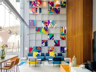 a lobby with a wall of colorful chairs and tables at Near Dubai Marina Canal 2BR with Pool and City Views Balcony, Studio One, Dubai Marina by Deluxe Holiday Homes in Dubai