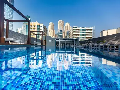 a large swimming pool with a city in the background at Near Dubai Marina Canal 2BR with Pool and City Views Balcony, Studio One, Dubai Marina by Deluxe Holiday Homes in Dubai