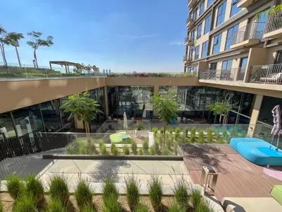 an apartment building with a patio and a swimming pool at Stylish 2BR Apartment Steps from Dubai Hills Mall in Dubai
