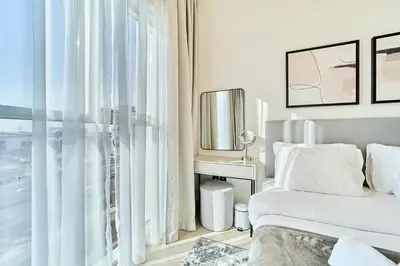 a white bedroom with a bed and a window at Stylish 2BR Apartment Steps from Dubai Hills Mall in Dubai