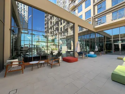 a large lobby with chairs and tables and windows at Stylish 2BR Apartment Steps from Dubai Hills Mall in Dubai