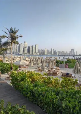 a beach with umbrellas and chairs and a city at Seven Hotel Palm jumeirah in Dubai