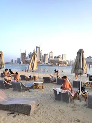 a group of people sitting on a beach with umbrellas at Seven Hotel Palm jumeirah in Dubai