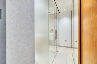 a glass shower door in a bathroom with white walls at GuestReady - Marina Gate Studio Suite in Dubai