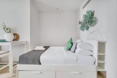 a white bedroom with a bed and a desk at GuestReady - Marina Gate Studio Suite in Dubai