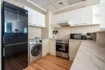 a kitchen with white cabinets and a washer and dryer at GuestReady - Modern living in Downtown Dubai in Dubai