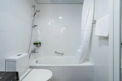 a white bathroom with a toilet and a bath tub at GuestReady - Modern living in Downtown Dubai in Dubai