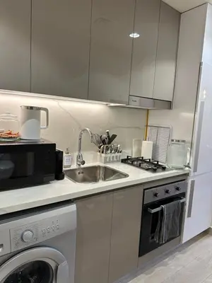 a white kitchen with a sink and a dishwasher at Azizi Riviera 44 in Dubai