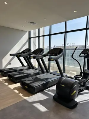 a row of treadmills in a gym with windows at Azizi Riviera 44 in Dubai