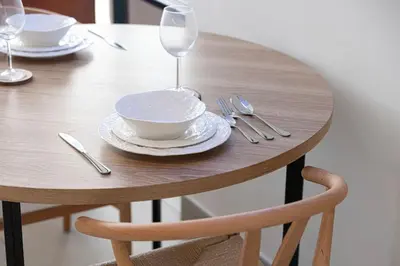 a wooden table with a bowl and plates and wine glasses at Urbane 1BR in Dubai Hills in Dubai