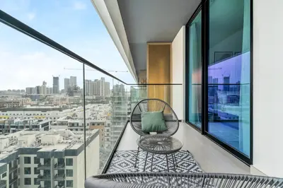 a chair on a balcony with a view of a city at Lovely 1BR flat wBalcony Gym & Pool in JVC in Dubai