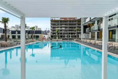 a large swimming pool with blue water in a building at Lovely 1BR flat wBalcony Gym & Pool in JVC in Dubai