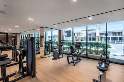 a gym with treadmills and cardio equipment in a building at Lovely 1BR flat wBalcony Gym & Pool in JVC in Dubai
